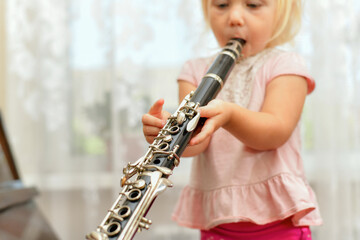 A little girl plays the clarinet. Teaching children music at a music school.