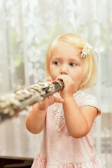 A little girl plays the clarinet. Teaching children music at a music school.
