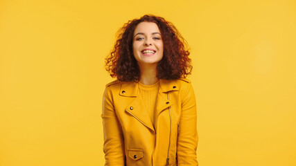 smiling young woman in jacket isolated on yellow