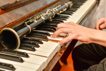 The clarinet lies on the black piano keys, the musician takes a chord on the white keys.
