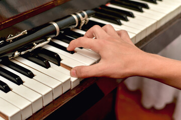 Fototapeta premium The clarinet lies on the black piano keys, the musician takes a chord on the white keys.