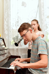 The girl plays the clarinet, and the guy with glasses accompanies her on the piano. Rehearsal and training at a music school.