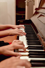 A girl and a guy play the piano in four hands. Rehearsal and training at a music school. - obrazy, fototapety, plakaty