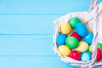 basket with colorful Easter eggs on a blue wooden background