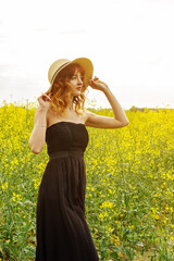 Redhead girl in a rapeseed field at sunset...