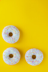 White Donuts with yellow background. Donuts with sprinkles