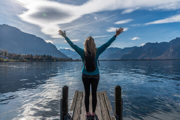 Unrecognized woman wearing sports clothes raising her arms and enjoying the views of the mountains.