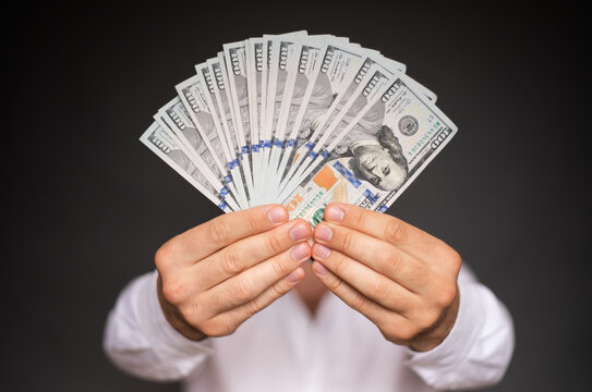Close up photo of young male hands holding the many of dollars of USA isolated on gray background