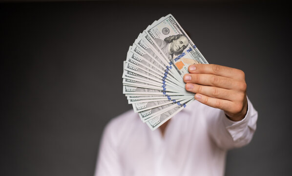 Close up photo of young male hands holding the many of dollars of USA isolated on gray background
