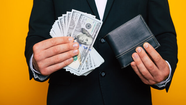 Close up photo of young successful businessman hands with wallet and bunch of dollars of USA