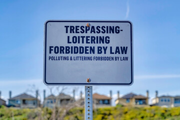 Trespassing Loitering Forbidden By Law sign against blue sky on a sunny day