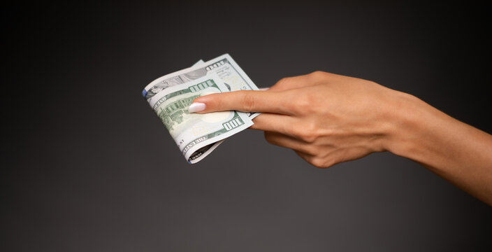 Close up photo of beautiful female hands holding the bunch of dollars of USA isolated on gray background. Economy, business and finance concept