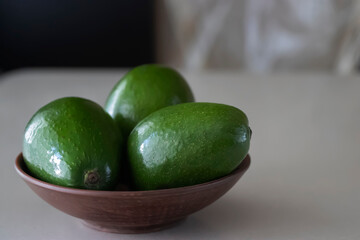 Green avocado in a brown plate on a light background.