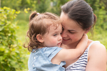 Little girl in denim dress in the arms of her smiling mom