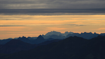 Bright lit yellow morning sky over Mount Grosser Mythen, Saentis and other mountains in the Swiss Alps.