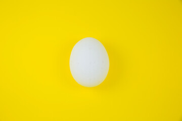 White egg on the yellow background. Copy space. Minimalism, original and creative photo. Beautiful wallpaper. Easter holidays.