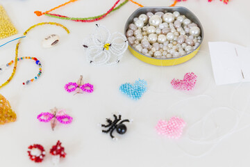 Creative, bright and colorful beads on the white table. Handicraft workplace. Beautiful diy jewelry and calming stress relieving hobby and activity