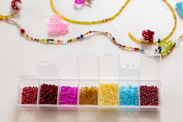 Creative, bright and colorful beads on the white table. Handicraft workplace. Beautiful diy jewelry and calming stress relieving hobby and activity