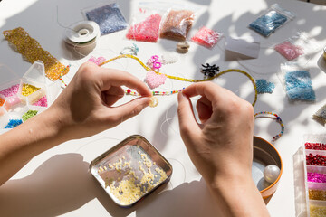 Beading workplace with hands in the process of handicraft. Beautiful diy jewelry and calming stress...