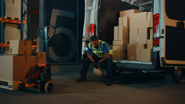 Handsome Latin Male Worker Wearing Hard Hat Loads Cardboard Boxes into Delivery Truck, Rests for a Minute. Online Orders, E-Commerce Goods, Food, Medicine. Tired Overworked Frontline Hero Doing Job