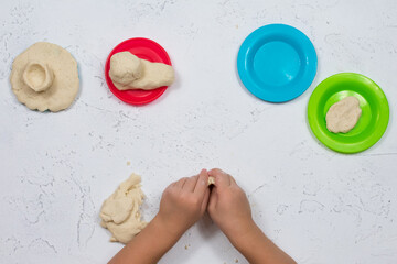 Children's hands are sculpted from salt dough. Development of fine motor skills of the hands. Development of children's creativity. Multi-colored plates.