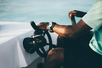 A close-up view of a hand with the watch of a black adult guy turning the steering wheel while...