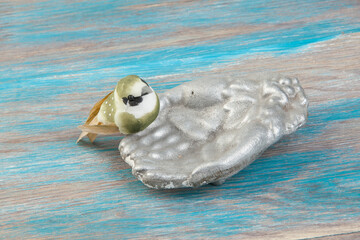 Old aluminum bird feeder on blue wooden background.