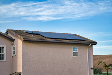 Solar panels on the pitched roof of a house with clouds and blue sky background