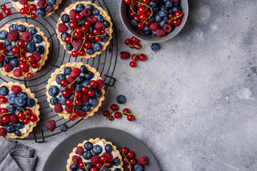 Tartlets with curd cream and fresh berries of raspberries, blueberries, red currants. Summer fruit baking. Copy space. Top view. 