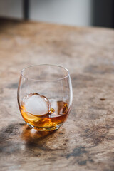 glass dram of whiskey whisky with sphere ice on wood table 