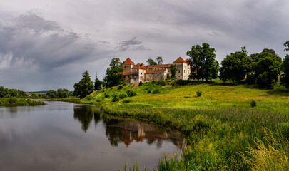 Fototapeta na wymiar Beautiful panorama of Svirzh castle by the river on a summer day, near Lviv.