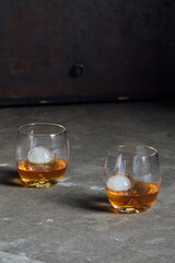 two drams of whiskey in a glass with sphere spherical ice