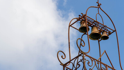 Close-up on the ornamental bells of a building, blue sky and cottony clouds