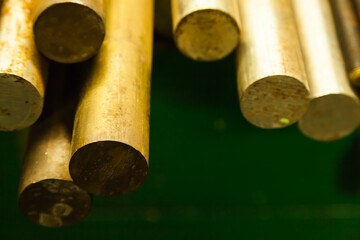Large-sized bronze round bars lie on the shelf, close-up.
