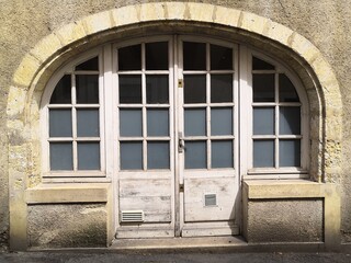 Close-up on an old white wooden door, topped with arched stones