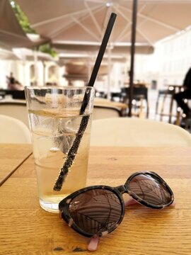 It's summer it's hot, close-up at a cafe terrace table, on a glass, sparkling water and a pair of sunglasses