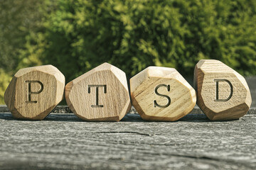 Letters PTSD written on wooden irregular blocks. Abbreviation for Posttraumatic stress disorder.