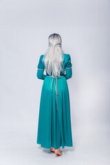 Full length portrait of a standing back princess in a medieval, fantasy, turquoise dress with ash hair and a silver crown posing isolated on a white background.
