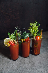 set of three Bloody Mary tomato brunch cocktail drink with celery, lemon, rosemary, pickles, olives garnish with gold straw in tall glass 