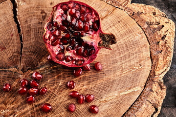 Close up of cut pomegranate on wooden board, fresh garnet background