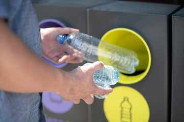 A person sorts and throws plastic bottles into the trash can to help the environment.The concept of ecology and waste recycling.