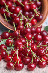 Bowl with red cherry on sackcloth background, top view