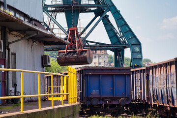 Fototapeta na wymiar Crane loading train wagon with coal from barge