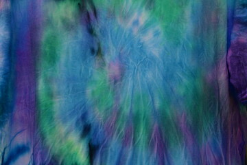 Abstract painted background. Multi-colored pattern in the shibori technique on a thin knitted fabric. Multi-color texture. batik.Textile shibori