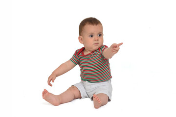 10 month old baby sitting on the floor and pointing on white background