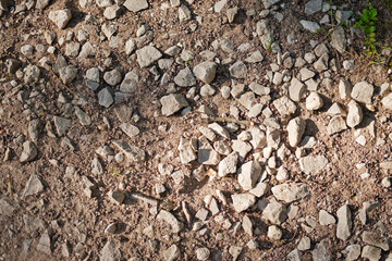 Top view of dirt road fragment. Dry land with stones. Abstract natural textured background.
