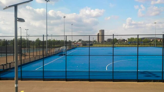 Empty blue hockey field in sports centre, playground lined by tall fence
