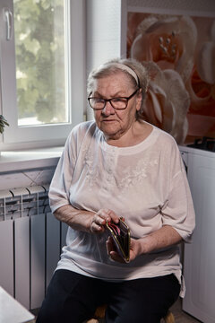 The Older Woman Counts The Money. An Elderly Woman Caucasian Old Woman Gray-haired Grandmother Takes Money Out Of Her Purse And Counts It. Old Hands Hold Bills.