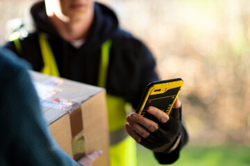Close up courier with smart phone delivering package