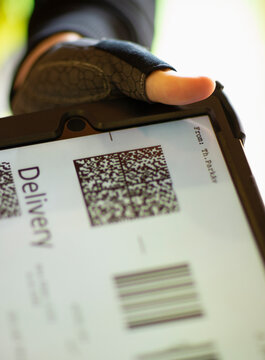 Close up courier holding digital tablet with delivery QR code